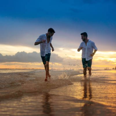 Young gay couple running on empty beach Florida